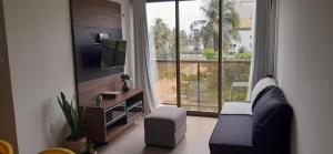 a living room with a couch and a large window at Apto climatizado à beira-mar c/ piscina-Intermares in Cabedelo
