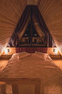 Little Wood House Gergeti في كازباجي: سرير كبير في غرفة مع نافذة