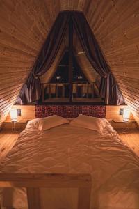 a large bed in a room with a window at Little Wood House Gergeti in Stepantsminda