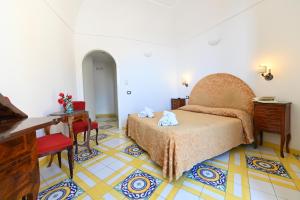 a bedroom with a bed and a table and a desk at Hotel Croce Di Amalfi in Amalfi