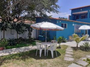a table and chairs under an umbrella in front of a blue house at Pousada Recanto das Oliveiras-Búzios in Búzios