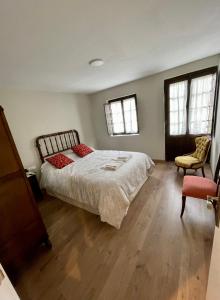 a bedroom with a bed and a chair and two windows at CASA NARCISA - Perfecta para familias y grupos - Valle del Silencio in San Clemente de Valdueza