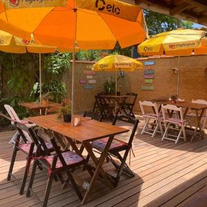 una mesa de madera y sillas con sombrillas en una terraza en Recanto das Margaridas, en Ilhabela