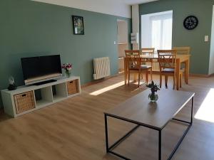 a living room with a television and a table with chairs at La petite Vineuilloise 10min de Châteauroux 40min zoo de Beauval in Vineuil