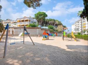 einen Spielplatz mit Rutschen und Spielgeräten in einem Park in der Unterkunft SeaHomes Vacations, LA MER BLEUE, beach&pool, PK, full equipped in Fenals Beach in Lloret de Mar