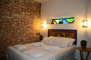 a bedroom with a white bed with a brick wall at Cunda Mavi Hotel in Ayvalık