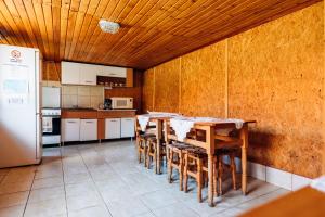 eine Küche mit Tisch, Stühlen und Kühlschrank in der Unterkunft Iris Panzio in Praid