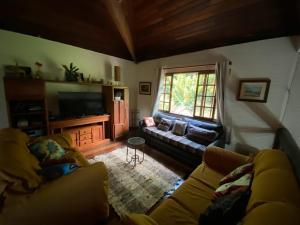 卢米亚Lumiar chalé colonial lareira deck para beira rio particular e reservado área de lazer pertinho centro do bairro的客厅里有一张沙发和一台电视