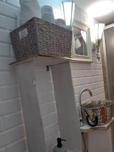 uma casa de banho com uma prateleira com uma cesta e um lavatório em Pensiunea Floarea Dornei em Şarul Dornei