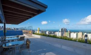 Un balcón con mesas y sillas y vistas al océano. en Flat Cabo Branco - Alto Padrao, en João Pessoa