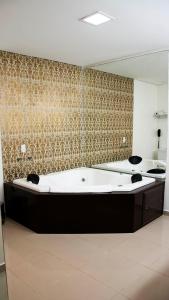 a large bath tub in a bathroom with a mirror at Golden Plaza Hotel in Porto Velho