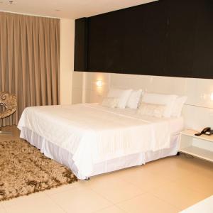 um quarto com uma cama grande com lençóis brancos e almofadas em Golden Plaza Hotel em Porto Velho