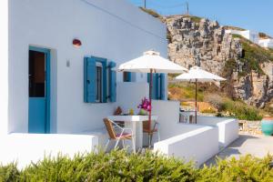 a white house with a table and chairs and umbrellas at Skaloto Studios in Artemonas