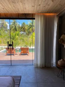 a bedroom with a large sliding glass door with a patio at Pedras Do Patacho Hotel Boutique Experience in Pôrto de Pedras