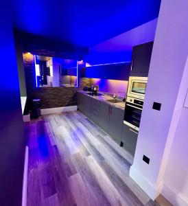 a kitchen with purple lights and a wooden floor at BREEZE SUITES - LUXURY GROUP ACCOM - SLEEPS 19 in Blackpool
