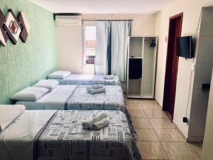 2 łóżka w pokoju hotelowym z ręcznikami w obiekcie Pousada Córdoba Cabo Frio w mieście Cabo Frio