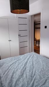 a white bedroom with a bed and a dresser at Apartamenty Obidowa in Obidowa