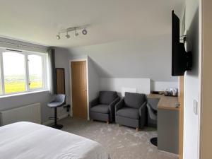 a bedroom with a bed and two chairs and a desk at Aultnagar Accommodation in Orkney