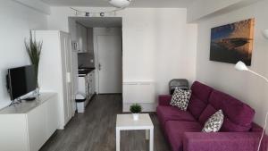 a living room with a purple couch and a tv at Estudio FARO TORROX-1ª línea playa in Torrox Costa