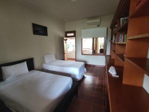 a room with two beds and a book shelf at Posada Hato el Diamante in San Luis de Palenque