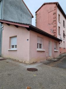 ein rosafarbenes Gebäude mit zwei Fenstern auf einer Straße in der Unterkunft Agréable maisonnette à proximité du centre-ville in Oyonnax