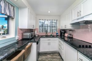 eine Küche mit weißen Schränken und rosa Fliesen in der Unterkunft Tropic Terrace #44 - Beachfront Rental condo in St Pete Beach