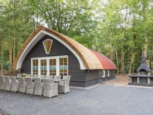 a house with a thatched roof with chairs in front at Beautiful group accommodation at nature reserve in De Bult