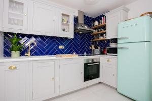 a kitchen with white cabinets and a refrigerator at Modern Garden Apartment Camden in London