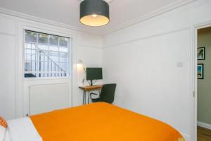 a bedroom with a bed and a desk and a window at Modern Garden Apartment Camden in London