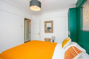 a bedroom with a bed with an orange bedspread at Modern Garden Apartment Camden in London