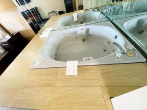 a bath tub in a bathroom with a wooden floor at Falls Lodge & Suites in Niagara Falls