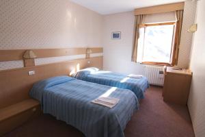 two beds in a small room with a window at Hotel Folgore in Passo Stelvio