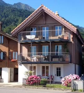 ein Haus mit Balkonen und Blumen davor in der Unterkunft Haus am See II in Därligen