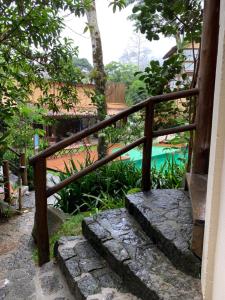 a wooden stairway leading to a garden with a pool at Estúdio no Condomínio Acquaville in Ilhabela