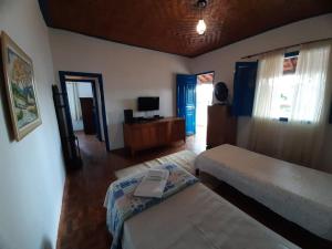 a bedroom with two beds and a television in it at Pousada Tabuleiro in Carmo do Rio Claro