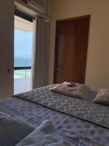 a bedroom with a large bed with a door and a window at Flat 2 suites com vista para o mar e lagoa. in Rio de Janeiro