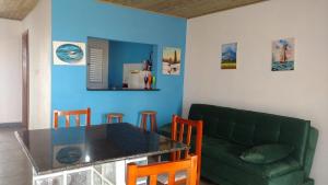 ein Wohnzimmer mit einem Tisch und einem grünen Sofa in der Unterkunft Recanto das Pedras - CASA Pedra Portuguesa - Com vista para o mar in Jaguaruna