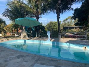 a swimming pool with an umbrella and a fountain at Recanto das Orquideas in Quatis +40 photos