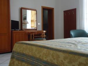 sypialnia z łóżkiem, biurkiem i lustrem w obiekcie Albergo Roma w mieście Casciana Terme