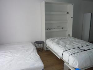 um quarto branco com 2 camas e uma mesa em Studio bord de mer en résidence MERVILLE FRANCEVILLE PLAGE em Merville-Franceville-Plage