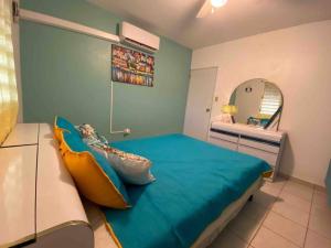 Schlafzimmer mit einem großen blauen Bett und einem Spiegel in der Unterkunft Pirata Family House• A 5 min de Poblado Boquerón in Cabo Rojo