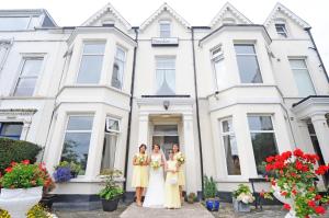 Un gruppo di tre donne in piedi davanti a una casa bianca. di Ennislare House Guest Accommodation a Bangor