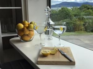 a table with two wine glasses and a bowl of lemons at Spectacular Lake Views in Rotorua