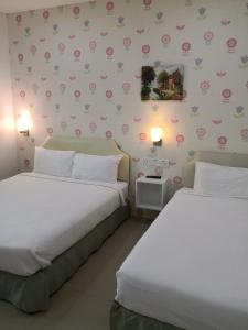 twee bedden in een kamer met bloemen aan de muur bij Summer Green Lodge in Kuantan