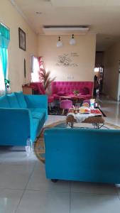 ein Wohnzimmer mit blauen Sofas und rosa Möbeln in der Unterkunft D-Rima Homestay Ruteng in Ruteng