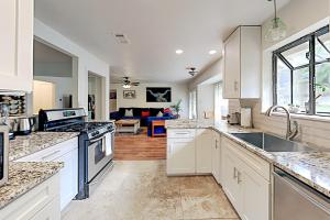 a kitchen with white cabinets and a living room at South Lamar Home in Austin