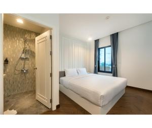 um quarto com uma cama branca e um chuveiro em Nine River Hotel em Ratchaburi
