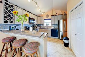 a kitchen with a counter with stools and a vase of flowers at Sunflower Hello in Port Aransas