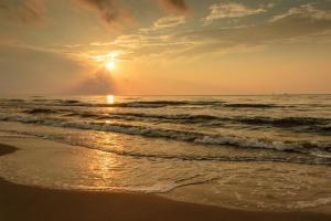 een zonsondergang op een strand met de oceaan bij Eskridge Gem Unit A in Port Aransas