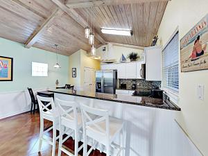 una cocina con barra con taburetes blancos en Sail Away at Pirate's Bay Unit 113, en Port Aransas